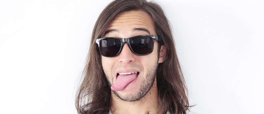 young man with long brown hair wearing sunglasses sticking tongue out