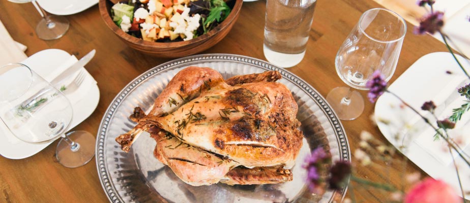 Aerial view of a Thanksgiving turkey on a silver platter next to water glasses and a green salad