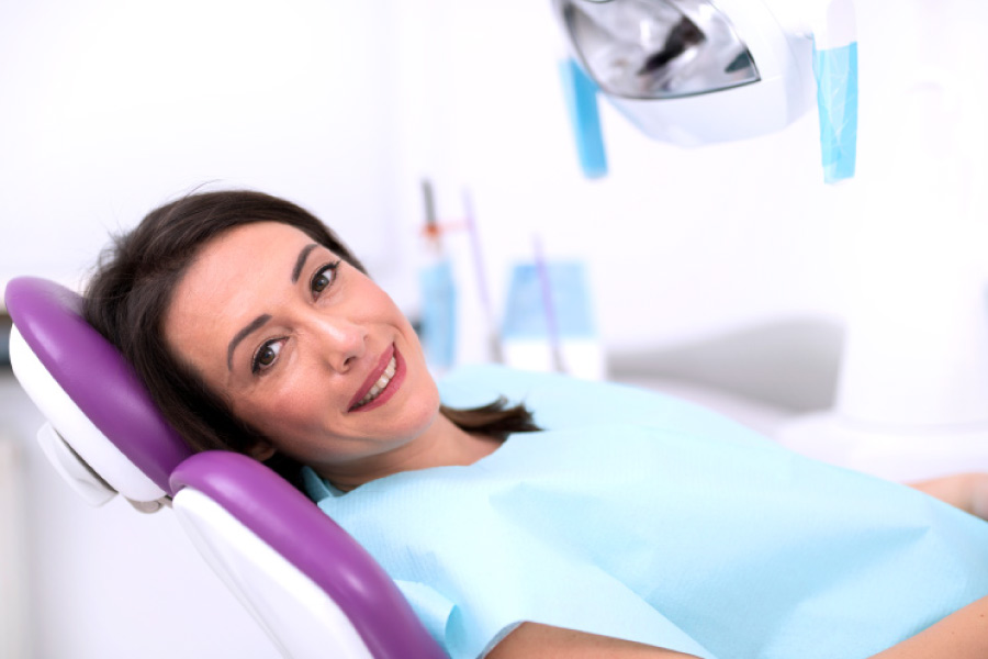 Smiling brunette woman looking sideways from the dental chair