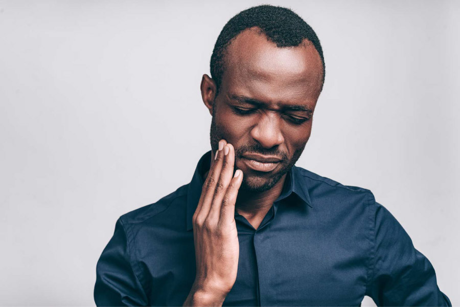 Man with his hand to his cheek because of tooth pain.
