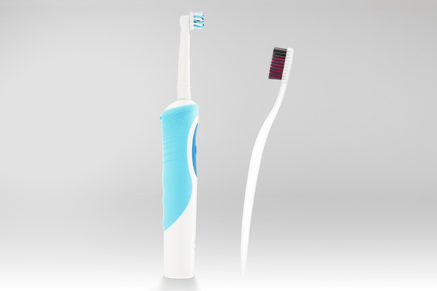 Photo of an electric toothbrush next to a regular toothbrush.