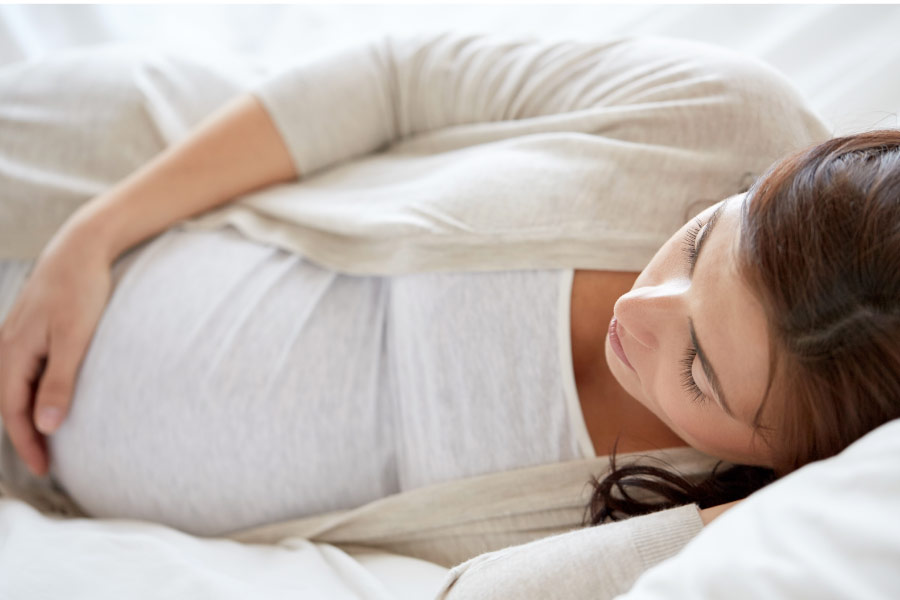 pregnant woman lays on her side and holds her belly