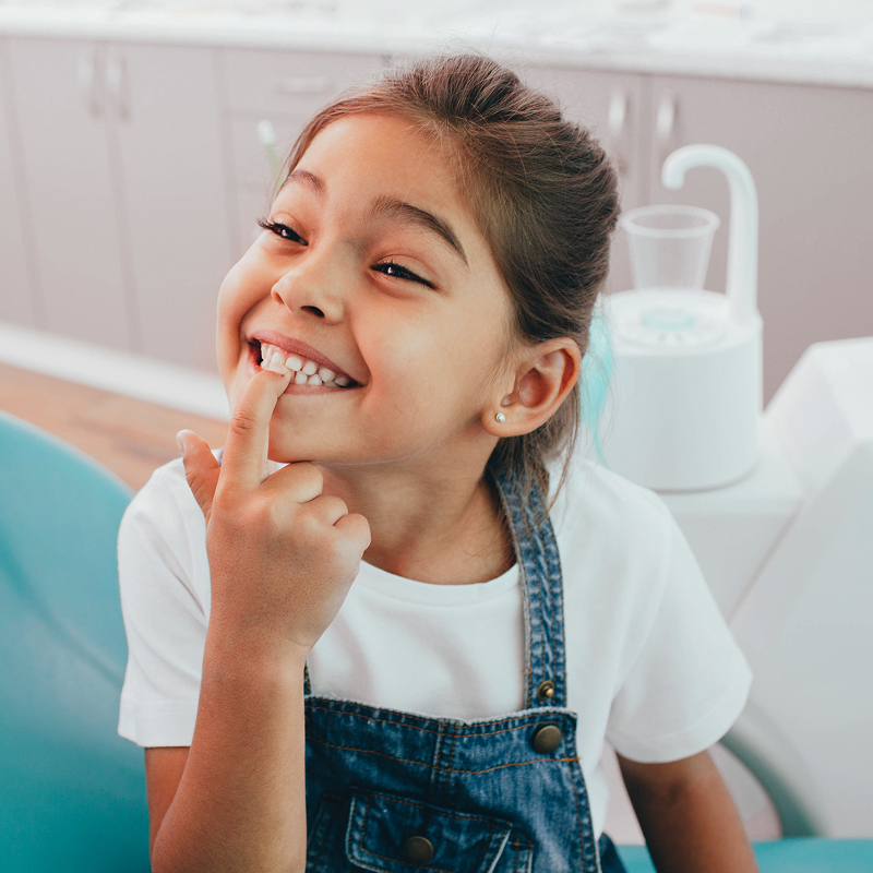 little girl pointing at her teeth