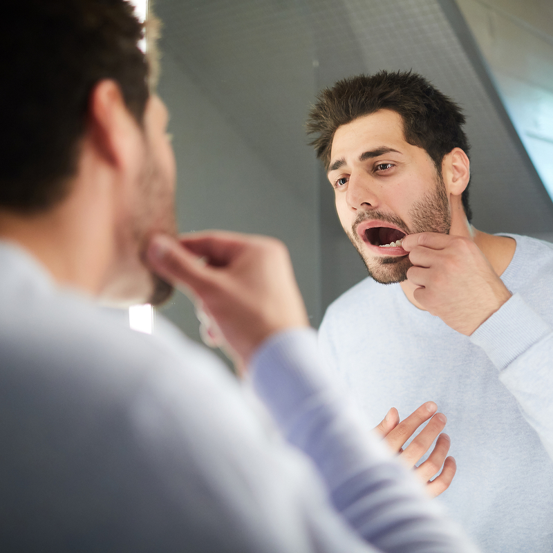 man flossing in mirror