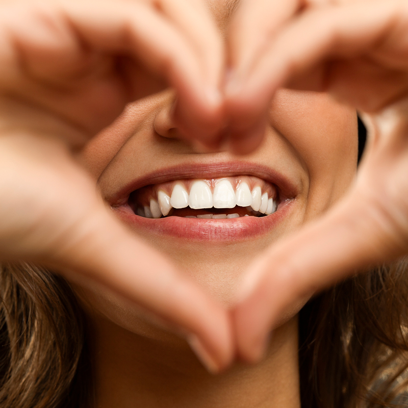 woman making heart around her smile