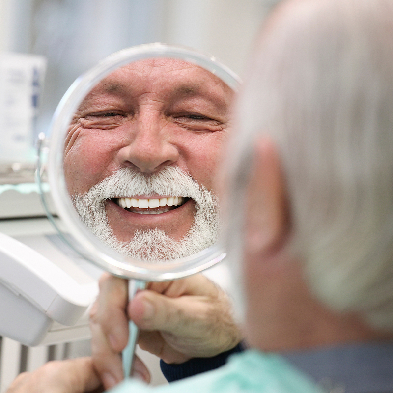 senior man smiling in mirror